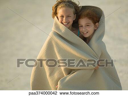 Two girls wrapped in blanket on beach View Large Photo Image Stock Image - Two girls wrapped in blanket on beach. Fotosearch