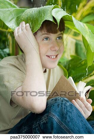 Boy with book sitting under leaf in rain View Large Photo Image Stock Photo - Boy with book sitting under leaf in rain. Fotosearch