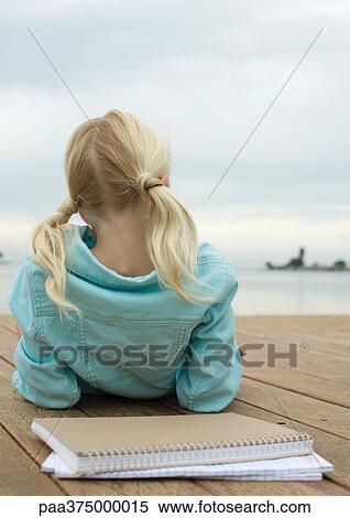 Girl lying on dock, notebooks behind her, rear view View Large Photo Image Stock Photography - Girl lying on dock, notebooks behind her, rear view. Fotosearch