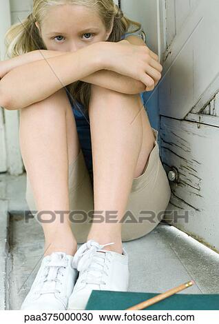 Girl sitting with arms folded on knees, homework on ground in front of her View Large Photo Image Stock Image - Girl sitting with arms folded on knees, homework on ground in front of her. Fotosearch