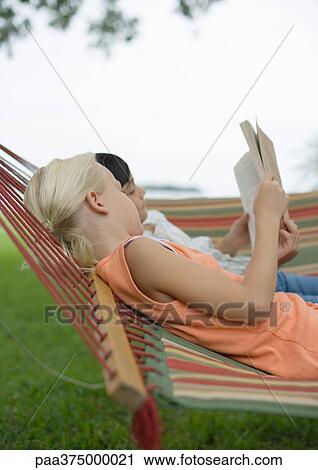 Girls lying in hammock reading book together View Large Photo Image Stock Image - Girls lying in hammock reading book together. Fotosearch
