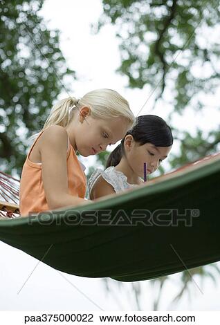 Two girls sitting in hammock, writing View Large Photo Image Stock Image - Two girls sitting in hammock, writing. Fotosearch