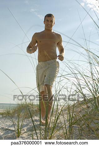 Man running in dunes on beach View Large Photo Image Stock Image - Man running in dunes on beach. Fotosearch