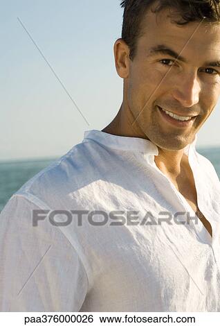 Man smiling, sea in background View Large Photo Image Stock Photograph - Man smiling, sea in background. Fotosearch