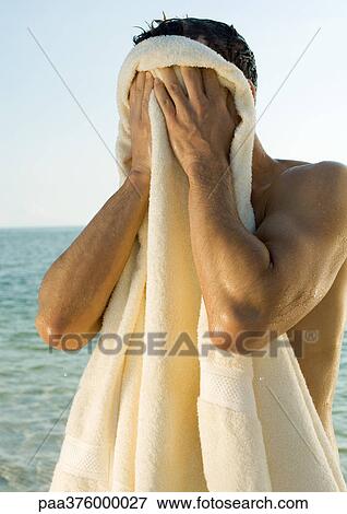 Man wiping face with towel, sea in background View Large Photo Image Stock Photo - Man wiping face with towel, sea in background. Fotosearch