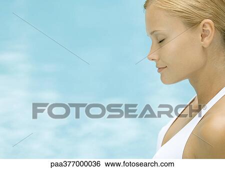 Woman closing eyes and smiling, water in background View Large Photo Image Stock Photograph - Woman closing eyes and smiling, water in background. Fotosearch