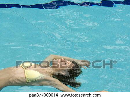Woman floating in pool, smiling View Large Photo Image Picture - Woman floating in pool, smiling. Fotosearch