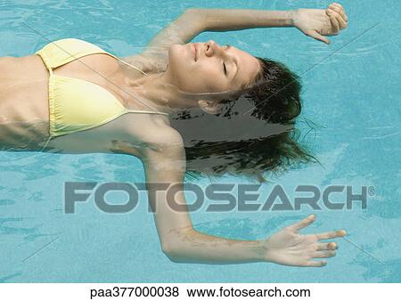 Stock Photo - Woman floating in pool. Fotosearch