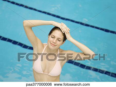 Woman standing in pool with hands on head and eyes closed View Large Photo Image Stock Photograph - Woman standing in pool with hands on head and eyes closed. Fotosearch