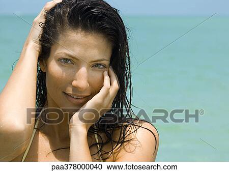 Woman holding head, smiling at camera, sea in background View Large Photo Image Stock Image - Woman holding head, smiling at camera, sea in background. Fotosearch