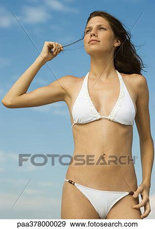 Woman in bikini standing holding strand of hair, looking away View Large Photo Image Stock Photo - Woman in bikini standing holding strand of hair, looking away. Fotosearch