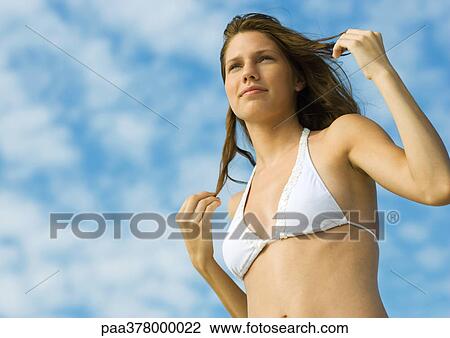 Woman in bikini standing with hands in hair, low angle view View Large Photo Image Stock Image - Woman in bikini standing with hands in hair, low angle view. Fotosearch