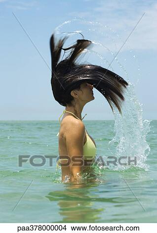 Woman standing in sea, tossing hair View Large Photo Image Picture - Woman standing in sea, tossing hair. Fotosearch