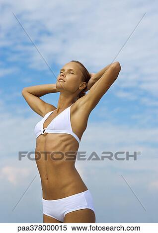 Woman standing in sun, hands behind head and eyes closed View Large Photo Image Stock Photography - Woman standing in sun, hands behind head and eyes closed. Fotosearch