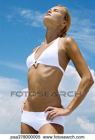 Stock Photography - Woman standing in sun with eyes closed. Fotosearch