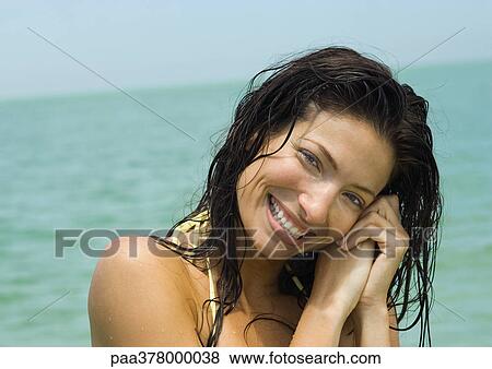Woman with wet hair smiling, sea in background View Large Photo Image Stock Photo - Woman with wet hair smiling, sea in background. Fotosearch