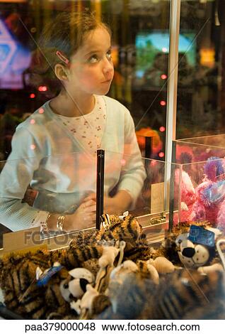 Girl looking through glass of toy grabbing game View Large Photo Image Stock Photo - Girl looking through glass of toy grabbing game. Fotosearch