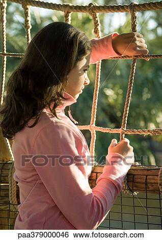 Stock Photograph - Girl looking through rope fence. Fotosearch