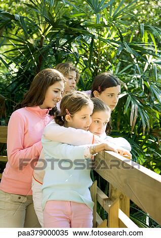 Stock Photography - Group of girls looking over wooden fence. Fotosearch