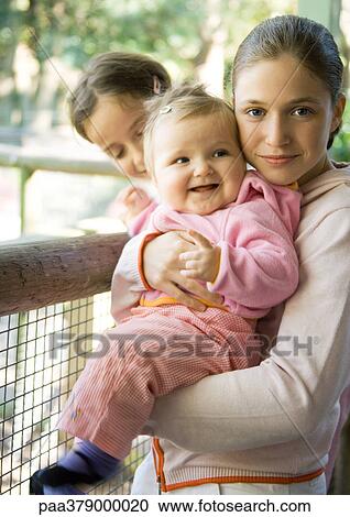 Preteen girl standing by railing, holding baby View Large Photo Image Stock Image - Preteen girl standing by railing, holding baby. Fotosearch