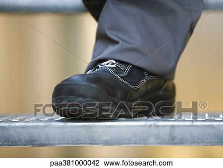 Stock Image - Man wearing safety shoes, close-up of shoe. Fotosearch