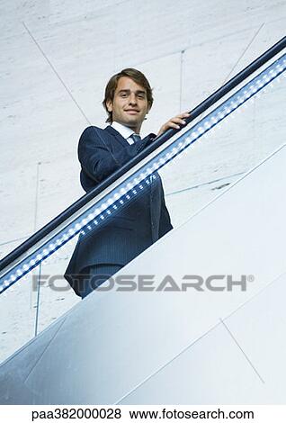Businessman going up on escalator View Large Photo Image Stock Photo - Businessman going up on escalator. Fotosearch
