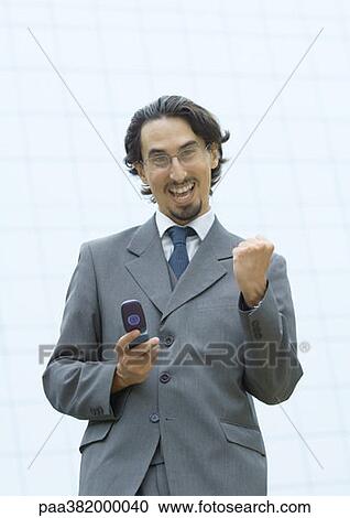 Businessman holding cell phone, making fist and shouting View Large Photo Image Stock Image - Businessman holding cell phone, making fist and shouting. Fotosearch