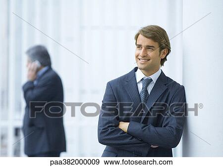 Businessman leaning against column, smiling View Large Photo Image Stock Photo - Businessman leaning against column, smiling. Fotosearch