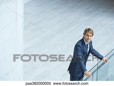 Stock Photography - Businessman leaning on railing, high angle view. Fotosearch