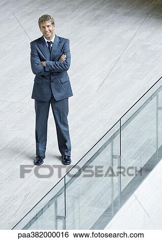 Businessman standing with arms folded, high angle view View Large Photo Image Stock Photograph - Businessman standing with arms folded, high angle view. Fotosearch
