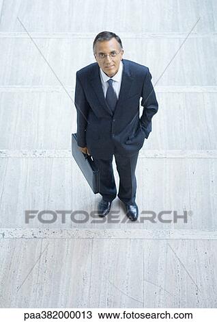 Businessman standing with briefcase, high angle view View Large Photo Image Stock Image - Businessman standing with briefcase, high angle view. Fotosearch