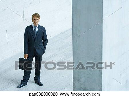 Businessman standing with briefcase, high angle view View Large Photo Image Stock Image - Businessman standing with briefcase, high angle view. Fotosearch