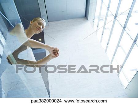 Picture - Businesswoman leaning against balcony, low angle view. Fotosearch