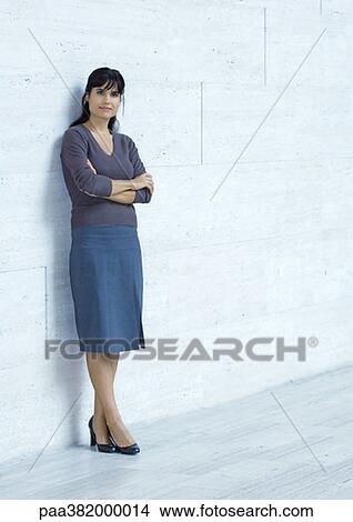 Picture - Businesswoman standing, leaning against wall, full length. Fotosearch