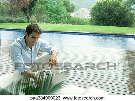 Casually dressed young executive working near edge of pool View Large Photo Image Stock Image - Casually dressed young executive working near edge of pool. Fotosearch