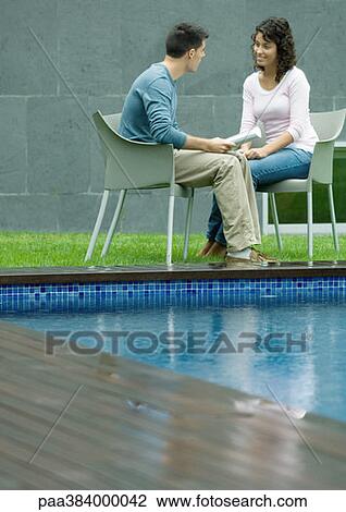 Stock Image - Casually dressed young executives working near edge of pool. Fotosearch