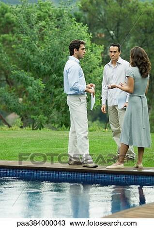Stock Image - Casually dressed young executives working near edge of pool. Fotosearch