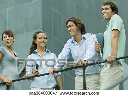Casually dressed young executives standing next to railing, low angle view View Large Photo Image Stock Photo - Casually dressed young executives standing next to railing, low angle view. Fotosearch