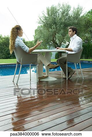 Stock Photograph - Casually dressed young executives working near edge of pool. Fotosearch