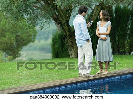 Man and woman standing near edge of pool with documents and cell phone View Large Photo Image Stock Image - Man and woman standing near edge of pool with documents and cell phone. Fotosearch