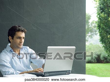 Stock Image - Man using laptop outdoors. Fotosearch