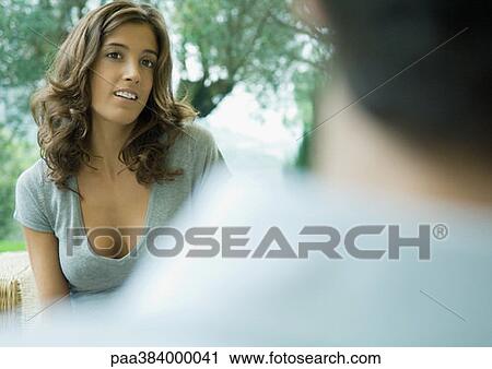 Stock Image - Woman facing man, outdoors, partial view. Fotosearch