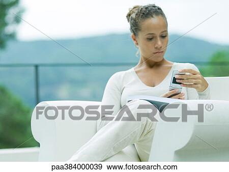 Woman sitting in armchair, outdoors, using cell phone View Large Photo Image Stock Photo - Woman sitting in armchair, outdoors, using cell phone. Fotosearch