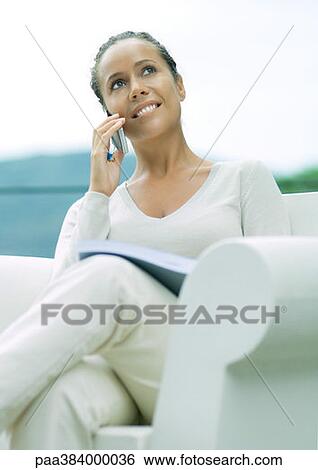 Woman sitting in armchair, using cell phone View Large Photo Image Stock Photograph - Woman sitting in armchair, using cell phone. Fotosearch