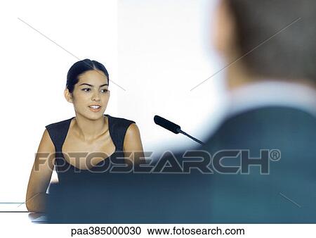 Businesswoman sitting next to microphone, man blurred in foreground View Large Photo Image Stock Image - Businesswoman sitting next to microphone, man blurred in foreground. Fotosearch