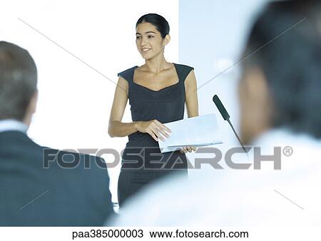 Stock Image - Executive woman standing next to microphone during seminar. Fotosearch