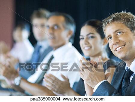 Picture - Executives sitting in seminar, clapping. Fotosearch