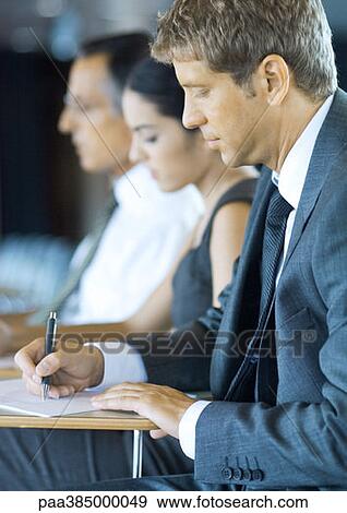 Executives sitting in seminar, taking notes View Large Photo Image Stock Photo - Executives sitting in seminar, taking notes. Fotosearch
