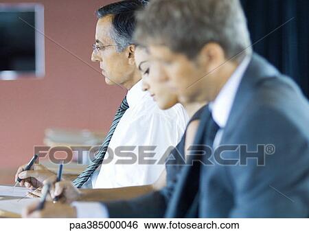 Stock Photograph - Executives sitting in seminar, taking notes. Fotosearch