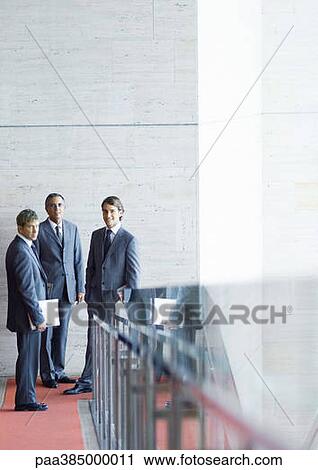 Stock Image - Executives standing, speaking. Fotosearch